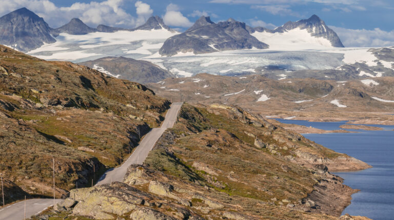 Vei gjennom fjellandskap snøkledde fjelltopper